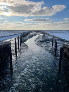 a body of water with a pier in the ocean at Ferienwohnung Watt n Deichblick in Friedrichskoog