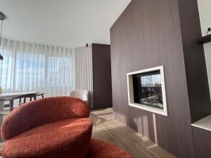 a living room with a red chair and a television at Pirate, op 100 meter van strand in Koksijde