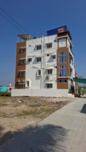 a large white building next to a brick building at Roshni Apartment - Ground Floor in Vishāram