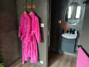a pink robe hanging in a bathroom with a sink at la penombre spa in Abbeville