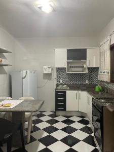 a kitchen with a black and white checkered floor at CAIPORA Hostel Lagoa in Saquarema