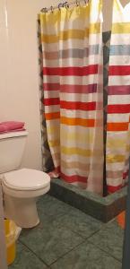 a bathroom with a toilet and a shower curtain at Cabaña La Isla in Isla Negra