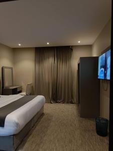 ein Hotelzimmer mit Bett und Flachbildfernseher in der Unterkunft فخامة العزيزية in Al-'Ula