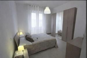 a white bedroom with a bed and a window at Il Mare a due Passi in Pesaro