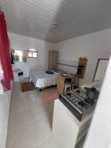 a room with a bed and a kitchen with a stove at Microcasa loft in São Pedro da Aldeia