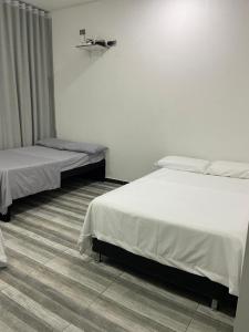 two beds in a room with white walls at Casa o Habitación in Villeta
