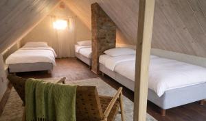 a attic room with two beds and a chair at Sepasauna holiday house in Joaveski