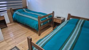 two twin beds in a room with wooden floors at Alojamiento Costanera in Laraquete