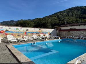 a swimming pool with chairs and a wall with a mural at Casa Obstei Caciulata in Caciulata