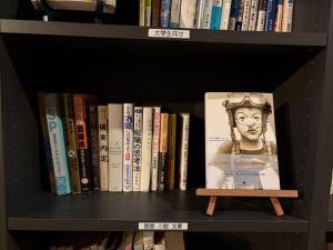 a book shelf full of books with a picture at 木の家ゲストハウス in Mito