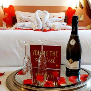 a bottle of wine on a tray next to a bed at Chambres d'hôtes Le Griffon 1855 in Saint-Laurent-des-Autels