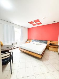 a bedroom with a bed and a red wall at Golfinho Hotel in São Vicente