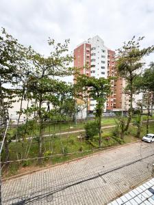 a park with trees and a car on a street at Golfinho Hotel in São Vicente