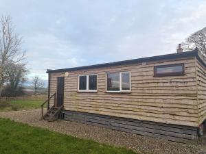 a small wooden house with a door and two windows at John D's Cabin Getaway in Derry Londonderry