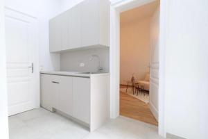 a white kitchen with a sink and a counter at Toplage beim Rathaus Grace Royal Designsuite in Vienna