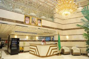 a woman is standing at a counter in a lobby at جوهرة مكة الفندقية in An Naqāʼ