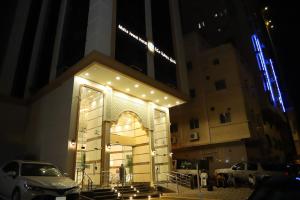 a building with an entrance with lights on it at night at جوهرة مكة الفندقية in An Naqāʼ