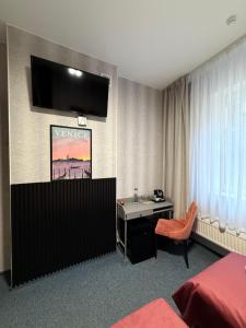 a hotel room with a desk and a tv on the wall at City Tour Apartamenty in Poznań