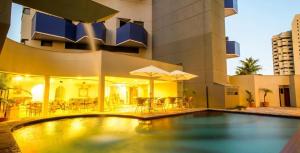 a swimming pool in front of a building at Duplex com Banheira no Centro de Campo Grande in Campo Grande