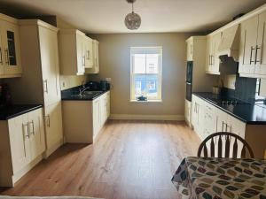 an empty kitchen with white cabinets and a window at Town Apartment in Ardara