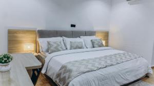 a bedroom with a large white bed and a table at French quarters apartments in Alaguntan