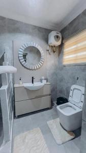 a bathroom with a toilet and a sink and a mirror at French quarters apartments in Alaguntan