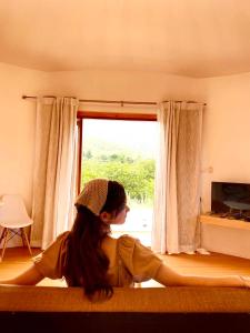 a woman laying on a bed looking out a window at Tropical pool villa คอฟฟี่มีเขาสาขา2 in HHQ