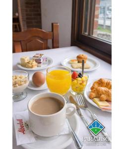 a table with a cup of coffee and plates of breakfast foods at Paradiso Hotel & Spa in Merlo