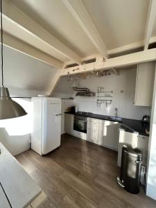 a kitchen with white appliances and wooden floors at Het schapenhuisje in Herkingen