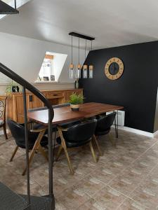 a dining room table with chairs and a clock on the wall at Chalet Spa - La Détente au Mont-Comi in Saint-Gabriel