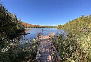 a wooden bridge over a lake with chairs on it at Chalet Spa - La Détente au Mont-Comi in Saint-Gabriel +7 photos