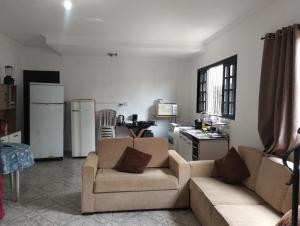 a living room with two couches and a kitchen at Casa de praia in Bertioga