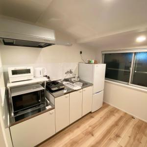 a small kitchen with white appliances and a window at AJITO Hostel 別館2 in Shingū