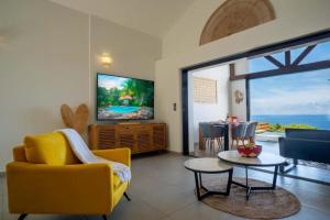 a living room with a yellow couch and a tv at Luxury Oceanfront Villa Heated Infinity Pool in Petite Île