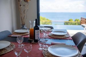 a table with plates and glasses and a bottle of wine at Luxury Oceanfront Villa Heated Infinity Pool in Petite Île