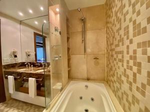 a bathroom with a tub and a shower and a sink at Suíte Refúgio Mountain Village Laje de Pedra 3003 in Canela +55 photos
