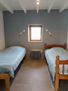 a bedroom with two beds and a table and a window at Gîte FABEL HAUT in Durfort