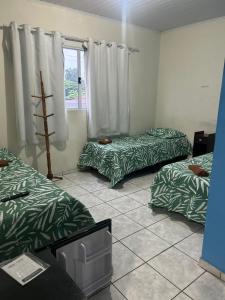a room with three beds and a window at pousada irmãs in Pindamonhangaba