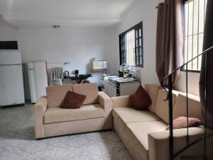 a living room with two couches and a kitchen at Casa de praia in Bertioga