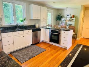 a kitchen with white cabinets and black counter tops at Cape Cod Retreat, Osterville Beach Pass in Osterville