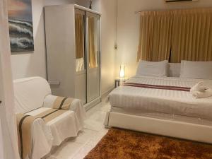 a white bedroom with a bed and a chair at OASIS VILLA Karon Beach in Karon Beach