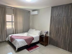 a bedroom with a bed and a wooden cabinet at Logo Luxury Guesthouse in Windhoek +12 photos