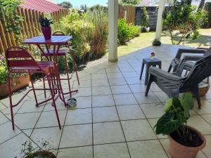 a patio with chairs and a table and a table at Chambre cosy avec piscine in Saint-Benoît