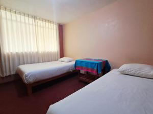 a small room with two beds and a window at Belen Achomani in Chivay
