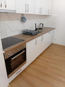 a kitchen with white cabinets and a stove top oven at Pristhine Stay Inn 19 in Prishtinë