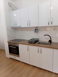 a kitchen with white cabinets and a sink at Pristhine Stay Inn 19 in Prishtinë +13 photos