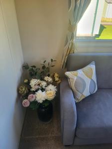 a blue couch with a vase of flowers next to a window at Nidd Way Holiday Let in Knaresborough