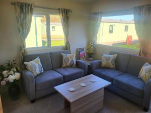 a living room with blue couches and a coffee table at Nidd Way Holiday Let in Knaresborough