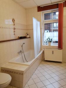 a bathroom with a tub and a toilet and a window at Ferienwohnung HARZgeNUSS in Wernigerode +59 photos