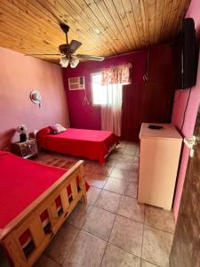 a room with two beds and a table and a refrigerator at Rincón Bosc in Ramallo